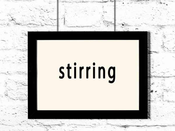 Siyah ahşap çerçeve, beyaz tuğla duvarda yazılar asılı. 