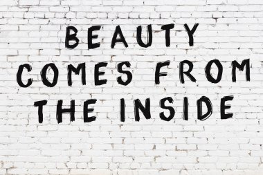 Beyaz tuğla duvara zekice alıntılar yazılı siyah bir yazı.