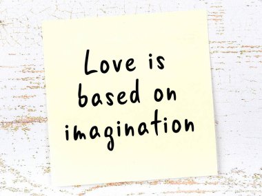 Tahta duvarda asılı sarı yapışkan nota elle yazılmış bilgece bir alıntı.