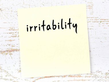 Tahta duvarda, el yazısıyla yazılmış asabiyeti olan sarı yapışkan bir not.