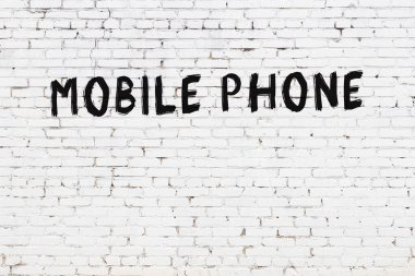 Üzerinde siyah boya ile el yazısıyla cep telefonu yazan beyaz tuğla bir duvar.