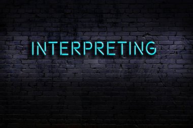 Üzerinde tuğla duvara karşı çeviri yazan neon tabela. Gece görünümü