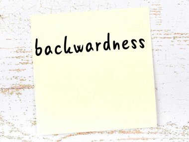 Ahşap duvardaki sarı yapışkan notta el yazısı geri kalmışlık var.