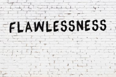 Beyaz tuğlalı duvar. Üzerinde siyah boya ile yazılmış kusursuz yazı var.