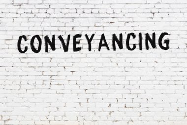 Üzerinde yazı olan beyaz tuğla duvar siyah boyayla el yazısıyla taşınıyor.