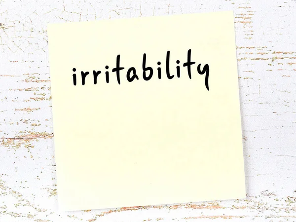 Tahta duvarda, el yazısıyla yazılmış asabiyeti olan sarı yapışkan bir not.