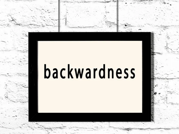 Μαύρο Ξύλινο Πλαίσιο Επιγραφή Backwardness Κρέμεται Λευκό Τοίχο Τούβλο — Φωτογραφία Αρχείου
