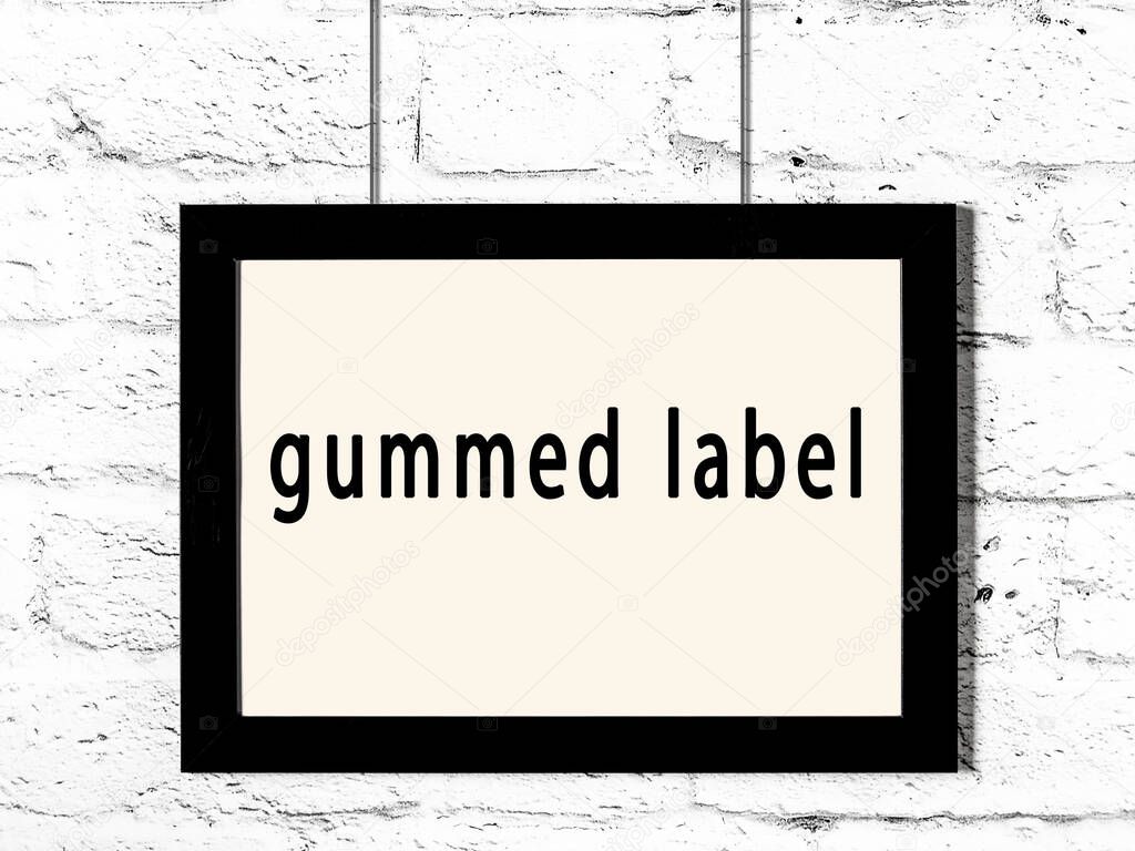 Black wooden frame with inscription gummed label hanging on white brick wall 