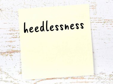 Tahta duvardaki sarı yapışkan notta el yazısıyla yazılmış dikkatsizlik var.