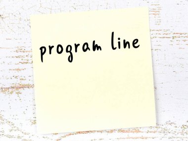 Tahta duvardaki sarı yapışkan notta el yazısıyla yazılmış program satırı var.