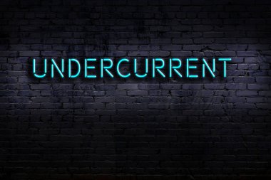 Tuğla duvara karşı altta yazılar olan neon tabela. Gece görünümü