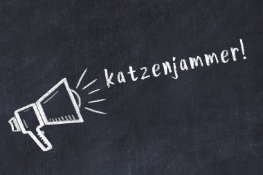 Hoparlörün tebeşir çizimi ve siyah masaya el yazısıyla yazılmış katzenjammer.