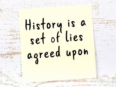 Sarı yapışkan not, ahşap duvarda el yazısıyla yazılmış zekice bir alıntıyla.