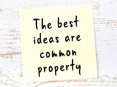 Tahta duvarda el yazısı motivasyon alıntısı olan sarı yapışkan not