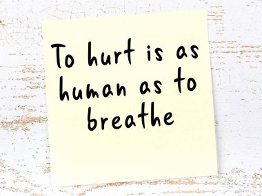 Tahta duvarda el yazısı motivasyon alıntısı olan sarı yapışkan not