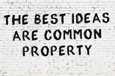 Beyaz tuğla duvara zekice alıntılar yazılı siyah bir yazı.