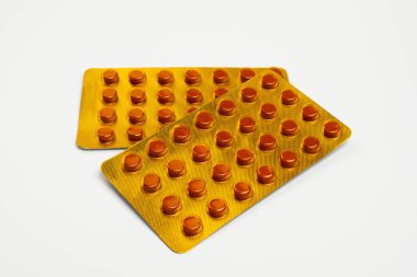 Beyaz bir zemin üzerinde izole edilmiş sarı tüberküloz tabletleri. Tüberküloz ilacı, tüketim döneminin dördüncü ayında paketlenmiştir..