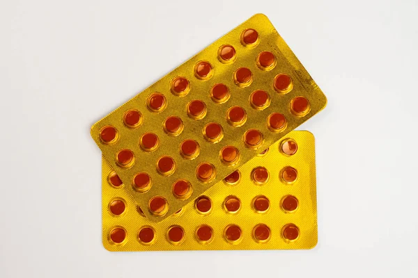 Beyaz bir zemin üzerinde izole edilmiş sarı tüberküloz tabletleri. Tüberküloz ilacı, tüketim döneminin dördüncü ayında paketlenmiştir..