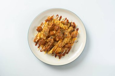 Çıtır Tavuk Doldurulmuş Patates, üstüne kremalı mayonez ve baharatlı sosla doldurulmuş tavuk, beyaz tabakta atıştırmak için mükemmel bir konforlu yemek tabağı yaratıyor..