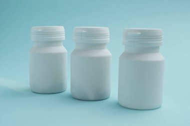 Mavi arka planda beyaz plastik şişeler. Tıbbi, kozmetik ve yiyecek için kullanılabilir..