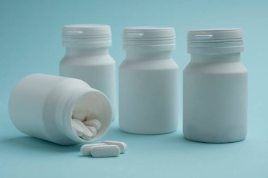 İlaç hapları ve haplar mavi arka planda şişeden dökülüyor. Sağlık hizmetleri, ilaç tedavileri ve ilaç endüstrisi için idealdir. Model.