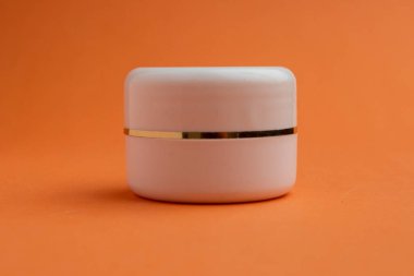 Turuncu zemin üzerine kolajen konmuş bir kavanoz sıkılaştırıcı krem. Creme modelleme, podyumda marka ambalajlama, cilt ürünleri, güneş kremi modelleme