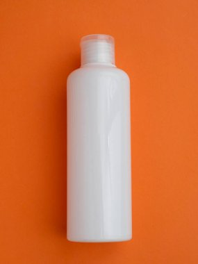 White Plastic bottle on a orange background. skin, body care. copy space. place for text
