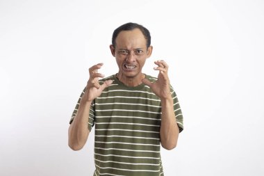 Beyaz çizgili yeşil gömlek giyen Asyalı bir adam kızgın bir ifade sergiliyor, dişlerini gösteriyor ve ellerini pençe gibi hareketlerle kaldırıyor, sanki öfke ya da hüsran içindeymiş gibi. Sade beyaz arkaplan konuyu vurgular.