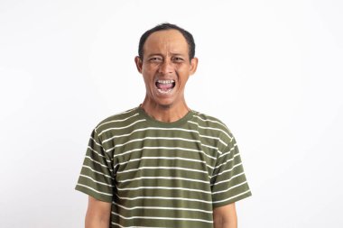 Öfkeli bir adamın bağırıp, nefretle baktığı, mavi arka plana karşı kızgın durduğu bir kare.