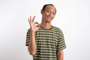 Beyaz çizgili yeşil tişört giyen Asyalı bir adam iki eliyle beyaz bir arka plana karşı 