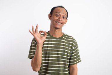 Beyaz çizgili yeşil tişört giyen Asyalı bir adam iki eliyle beyaz bir arka plana karşı 