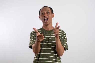 Beyaz çizgili yeşil tişört giyen Asyalı bir adam sağlam sarı bir arka plana güvenerek başparmak sallıyor ve gülümsüyor. Bu resim pozitifliği, onayı ve tatmini resmediyor.