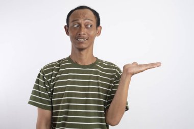 Düşünceli, sıradan, yeşil gömlekli genç bir adamın portresi beyaz arka planda izole edilmiş bir yeri işaret ediyor.