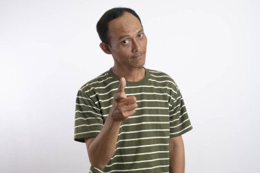 Beyaz çizgili yeşil tişört giyen Asyalı bir adam sağlam sarı bir arka plana güvenerek başparmak sallıyor ve gülümsüyor. Bu resim pozitifliği, onayı ve tatmini resmediyor.