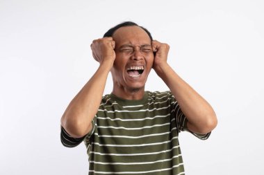 Duygusal deli deli genç erkek yüksek sesle çığlıklar ve öfke ile, stresli olmak ve panik içinde, kaşlarını çatıyor yüz, beyaz beton duvar üzerinde izole. Olumsuz insani duygular, duygular, tepki kavramı