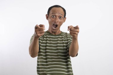 Yeşil tişörtlü Asyalı bir adam, sanki bir reklam aracı için beklenmedik bir şey fark ediyormuş gibi, şaşırmış ve meraklı bir ifadeyle yan tarafı işaret ediyor. Beyaz arka plan onun heyecanlı ifadesini vurguluyor..