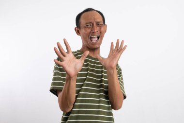 Beyaz arka planda yeşil tişörtlü genç Asyalı bir adam. Şaşırmış ve heyecanlı bir ifadesi var. Elleri havada ve ağzı açık. Sürprizle ilgili konular için ideal