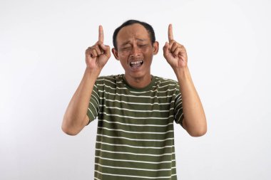 Asyalı bir adam, beyaz çizgili yeşil bir gömlek giyiyor, iki eli de yukarı bakıyor ve bir ilgi ifadesi sergiliyor. Reklam medyası için bir ürünü işaret etme kavramı.