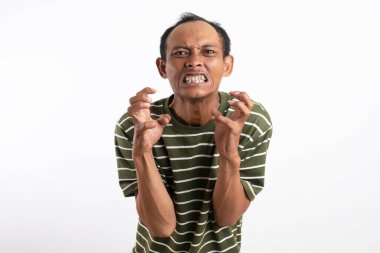 Beyaz çizgili yeşil gömlek giyen Asyalı bir adam kızgın bir ifade sergiliyor, dişlerini gösteriyor ve ellerini pençe gibi hareketlerle kaldırıyor, sanki öfke ya da hüsran içindeymiş gibi. Sade beyaz arkaplan konuyu vurgular.