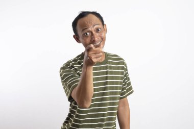 Beyaz çizgili yeşil tişört giyen bir adam sanki güçlü bir ifade ya da emir veriyormuş gibi kameraya yoğun ve odaklanmış bir ifadeyle bakar. Açık mavi arka plan iddiasını vurguluyor.