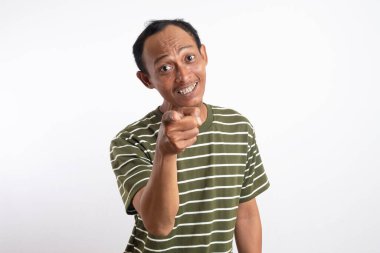 Beyaz çizgili yeşil tişört giyen bir adam sanki güçlü bir ifade ya da emir veriyormuş gibi kameraya yoğun ve odaklanmış bir ifadeyle bakar. Açık mavi arka plan iddiasını vurguluyor.