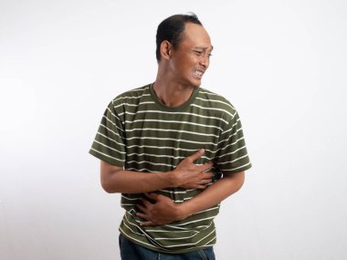 Beyaz çizgili yeşil gömlek giyen bir adam, midesi ağrıyan bir ifadeyle karnını tutar, bu da mide ağrısını ya da rahatsızlığını gösterir. Açık mavi arka plan sıkıntısını vurguluyor.