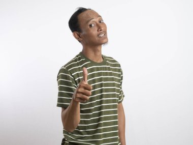 Beyaz çizgili yeşil gömlekli bir adam gülümsüyor ve olumlu bir jest yapıyor ve onaylıyor. Açık mavi arka plan, onun neşeli ve kendinden emin tavırlarını vurguluyor..