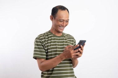 Tarafsız bir arkaplanda akıllı telefonu tutan yakışıklı bir adam gülümsüyor.