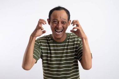 Beyaz çizgili yeşil gömlek giyen Asyalı bir adam kızgın bir ifade sergiliyor, dişlerini gösteriyor ve ellerini pençe gibi hareketlerle kaldırıyor, sanki öfke ya da hüsran içindeymiş gibi. Sade beyaz arkaplan konuyu vurgular.