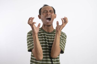 Beyaz çizgili yeşil gömlek giyen Asyalı bir adam kızgın bir ifade sergiliyor, dişlerini gösteriyor ve ellerini pençe gibi hareketlerle kaldırıyor, sanki öfke ya da hüsran içindeymiş gibi. Sade beyaz arkaplan konuyu vurgular.