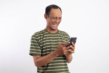 Asyalı adam rahatsız edici bir ifadeyle akıllı telefon kullanıyor.