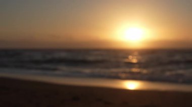 Yumuşak odaklı altın gün batımı huzur dolu okyanus dalgalarını aydınlatarak el değmemiş kumlu sahilde usulca yıkanarak ılık ışık ve huzurlu atmosferle sakin bir sabah deniz manzarası yaratıyor.
