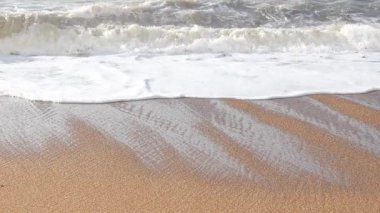 Yumuşak okyanus dalgaları altın kumlu kıyılara yuvarlanıyor, parlak güneş ışığı altında yumuşak dalgalanan dalgalar yaratıyor.