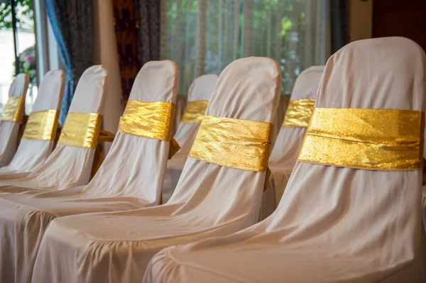 Chaises de mariage en rangée décorées avec un ruban de couleur dorée — Photo